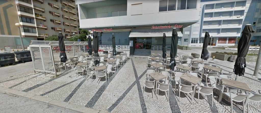 Outdoor terrace seating at Johnny Ringo in Figueira da Foz with tables, chairs, and closed umbrellas in front of the restaurant